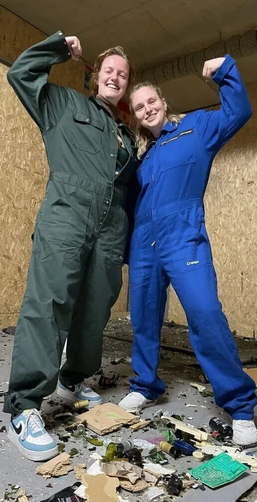 Close-up of two people smiling in rage room gear