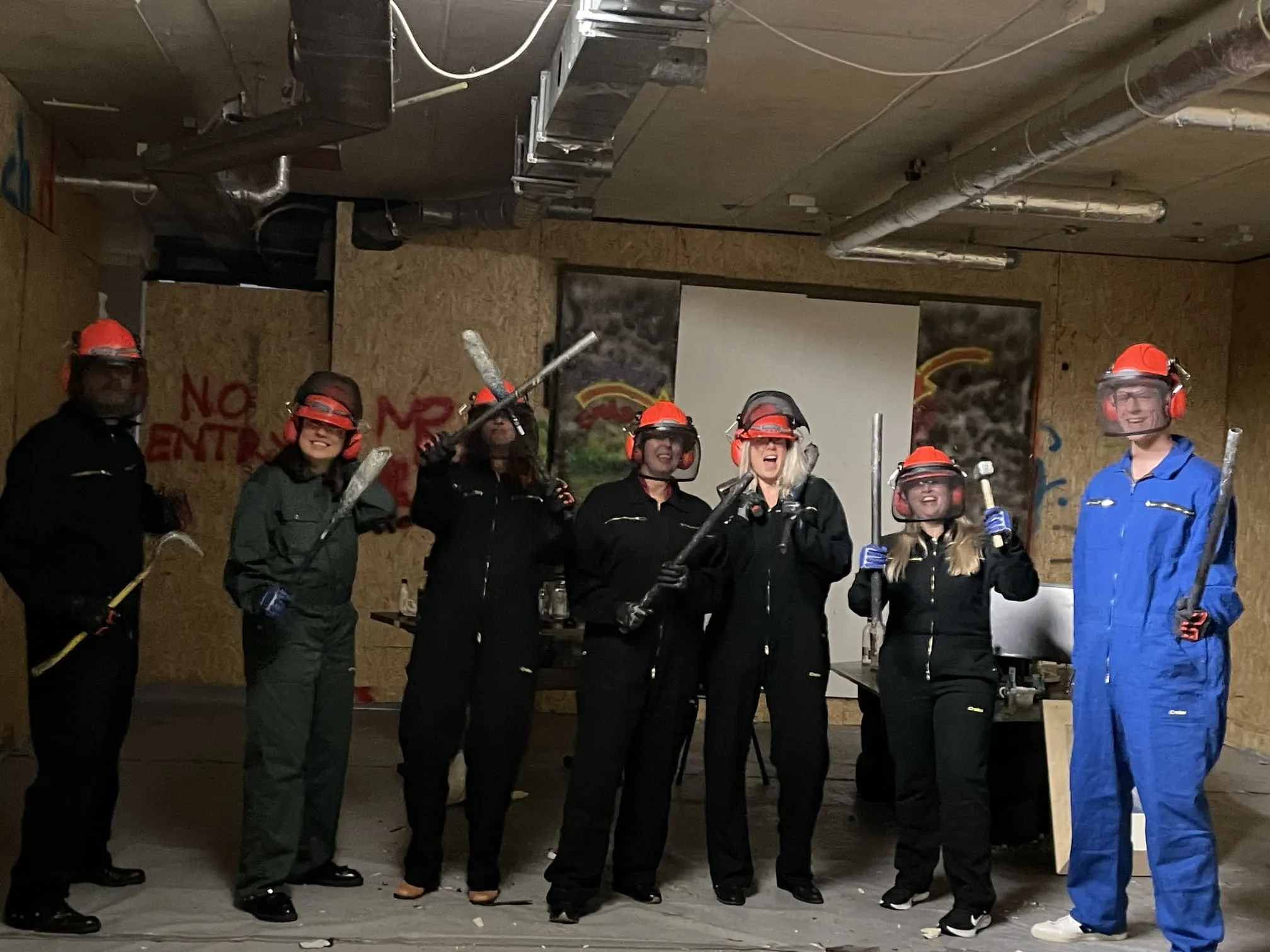 Groep mensen in beschermingspak poseert samen in rage room