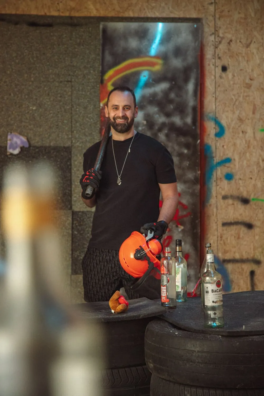 Man smiling in rage room holding helmet and bat